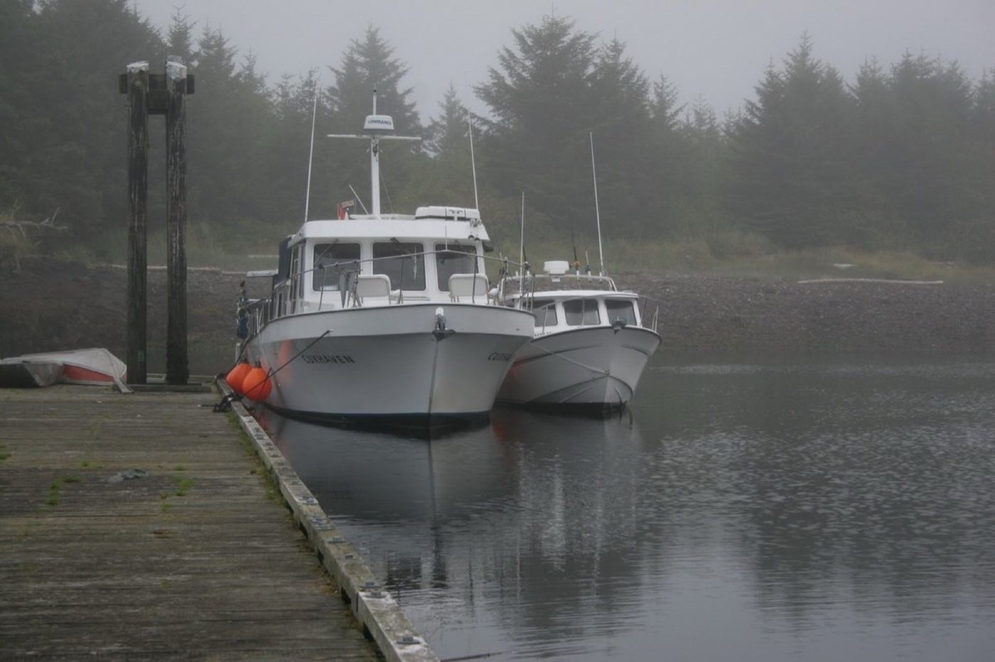 Two boats moored at a wooden dock in coastal fog (placeholder photo)